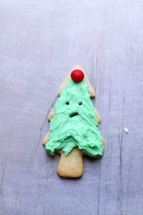 A Christmas tree cookie with a sad face.