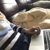 Kristen sitting on the couch with her laptop.