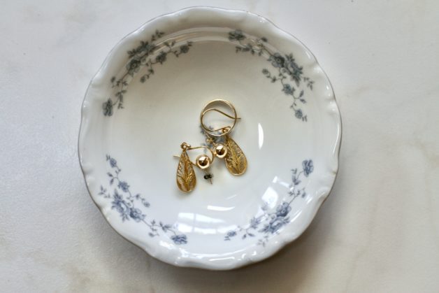A blue china bowl holding jewelry.
