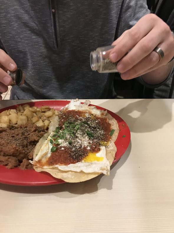 A person pouring pepper on a plate of eggs.