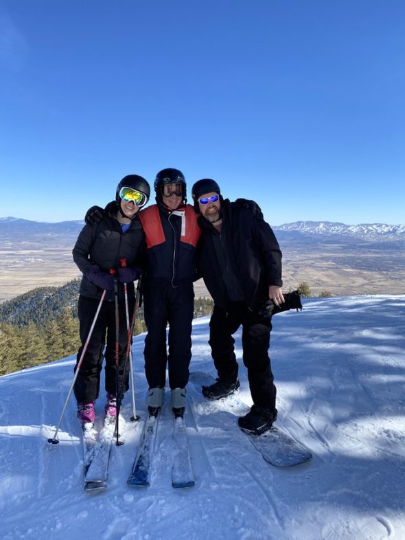 Kristen with her dad and brother on a ski slope.