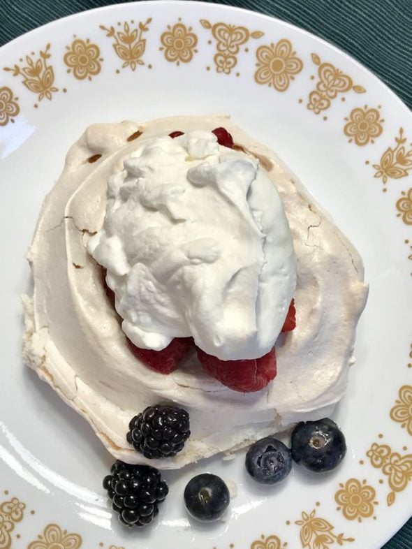 A meringue shell topped with whipped cream and berries.