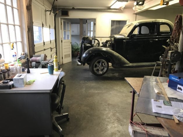A workshop with an old black car in it.