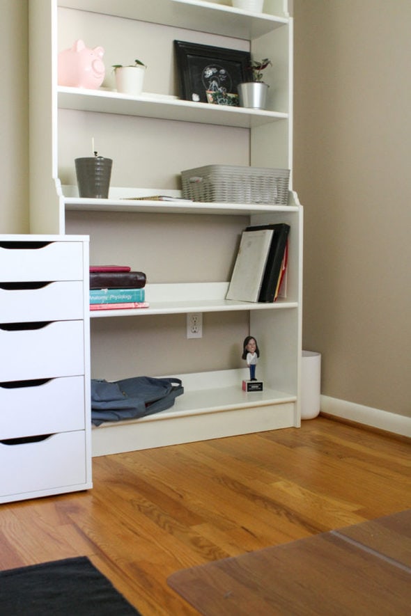 A white bookshelf in a room with oak floors.