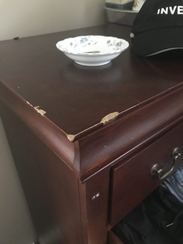 A dresser with damage around the top edges.