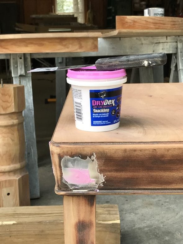 a table with pink wood filler in a hole.