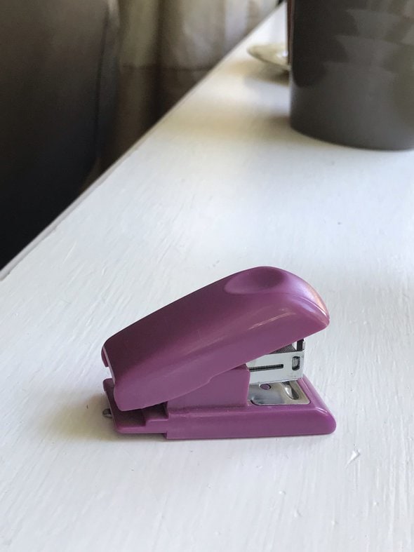 Small purple stapler on white counter.