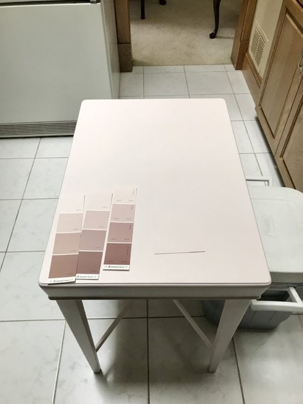 A pink table with paint chips on it.