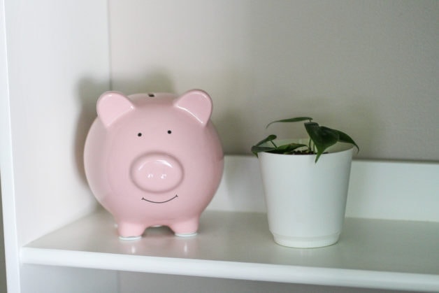 A pink piggy bank on a bookshelf.