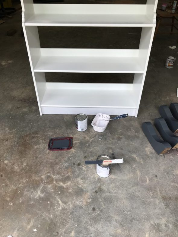 A white painted bookshelf in a garge.