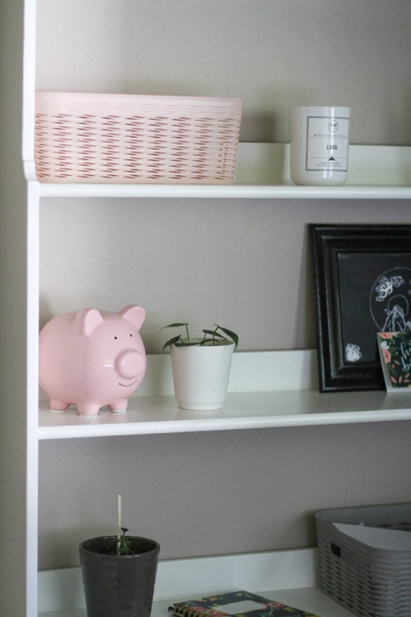 A pink pig on a bookshelf.