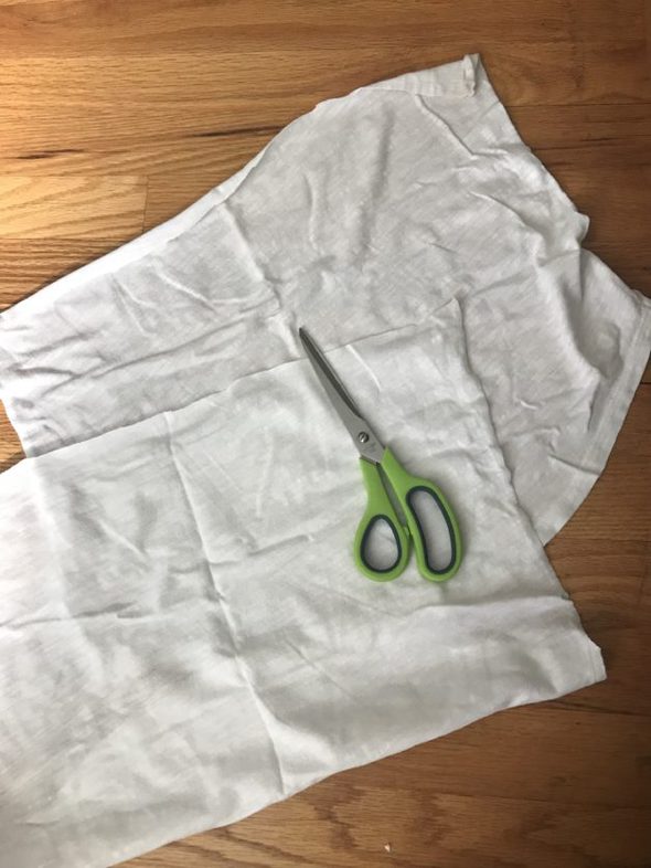 A green pair of scissors and two white rags.