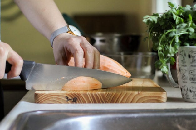 Kristen chopping a sweet potato.