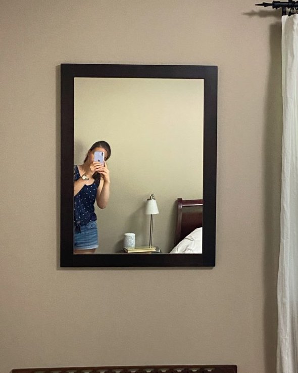 Kristen shown in a reflection in a wall mirror.