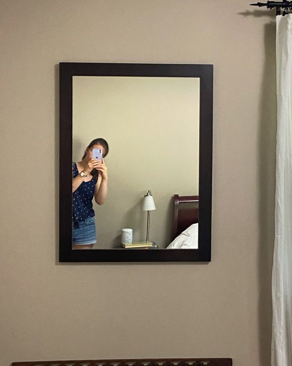 Kristen shown in a reflection in a wall mirror.