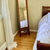 A floor mirror in a room with khaki walls.