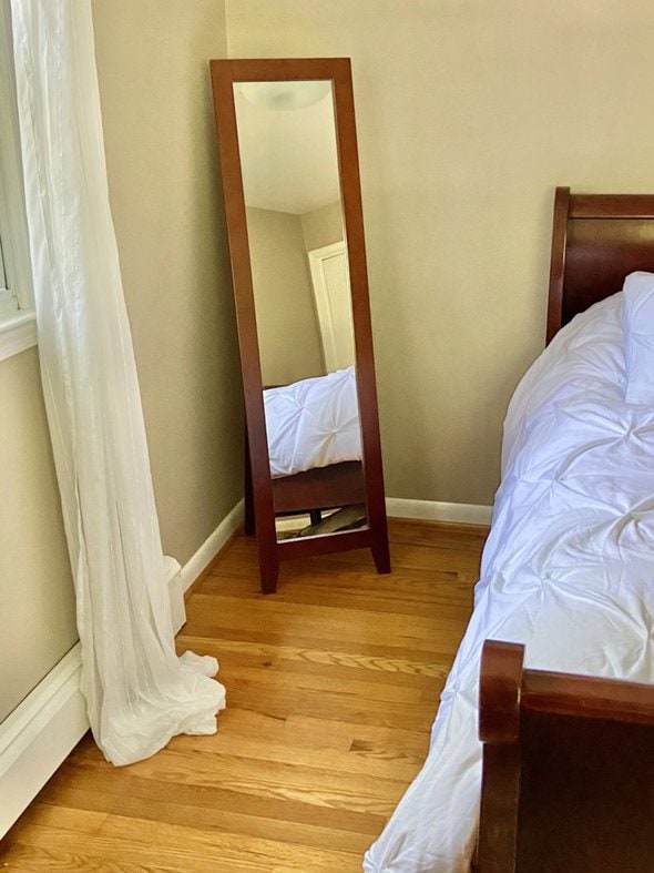 A floor mirror in a room with khaki walls.