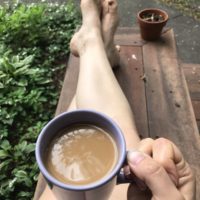 Kristen on a bench holding a coffee mug.