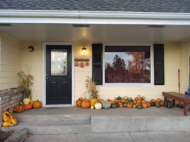 a porch piled with pumpkins.