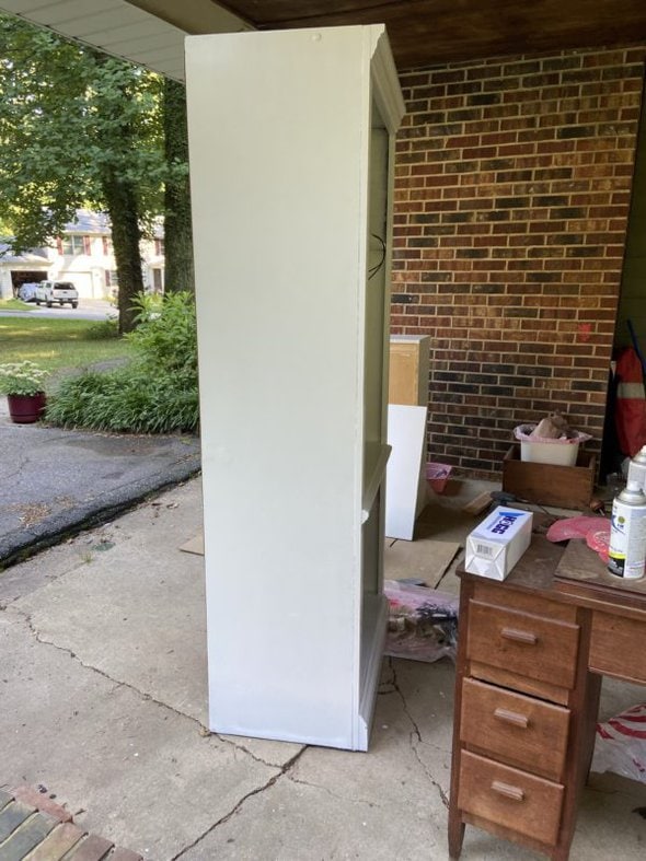 Tall white bookshelf in carport.