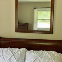 Wood-framed wall mirror above bed.