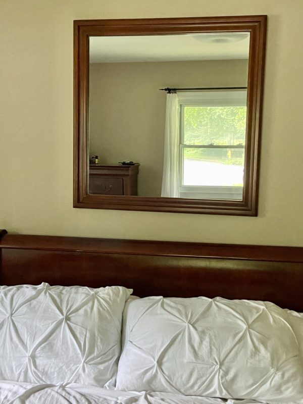 Wood-framed wall mirror above bed.