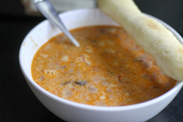 bowl of pasta soup with a breadstick.