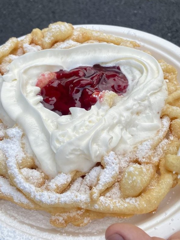funnel cake topped with whipped cream and strawberries.