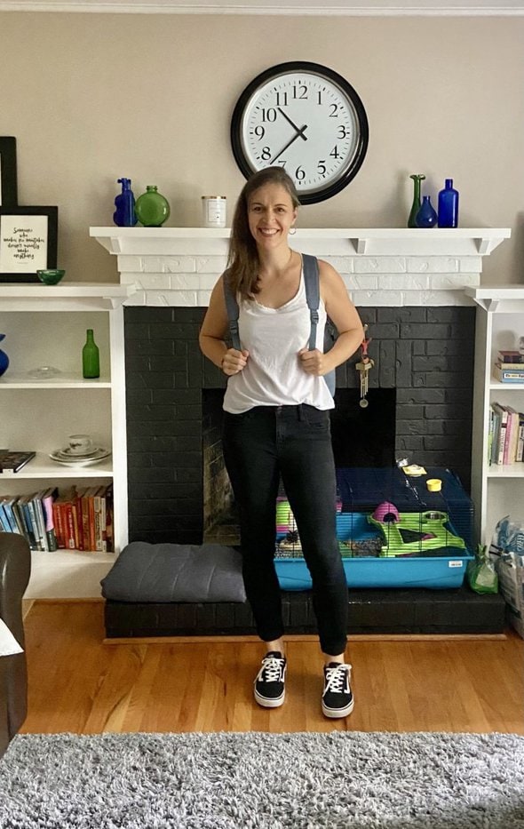 Kristen wearing a backpack, standing in her living room.