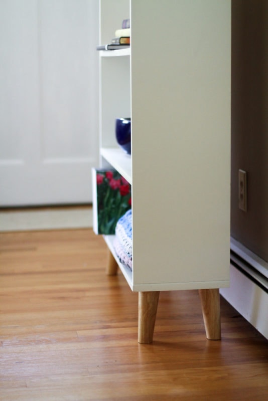 White shelf with wood legs.
