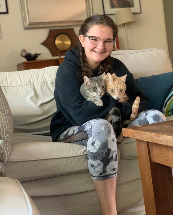 A girl holding two cats.