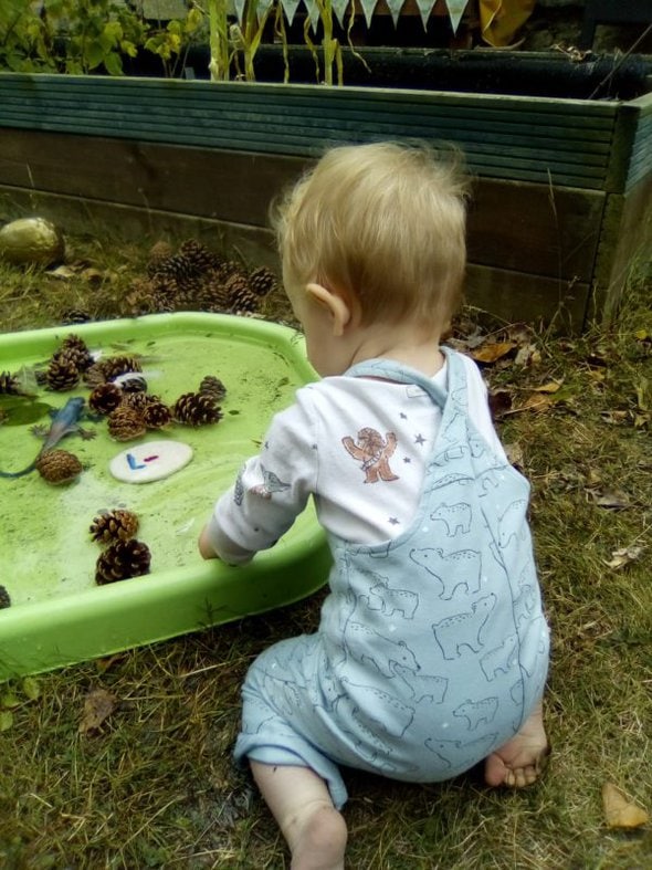 a baby playing in a pool of water.