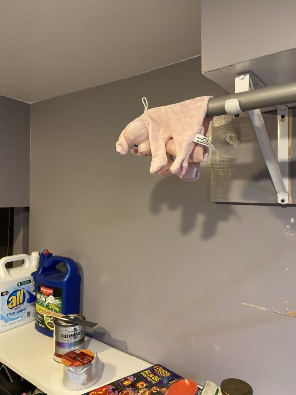 pig puppet hanging on a clothing rack.