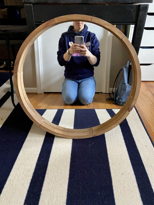 A round mirror with Kristen reflected in it.
