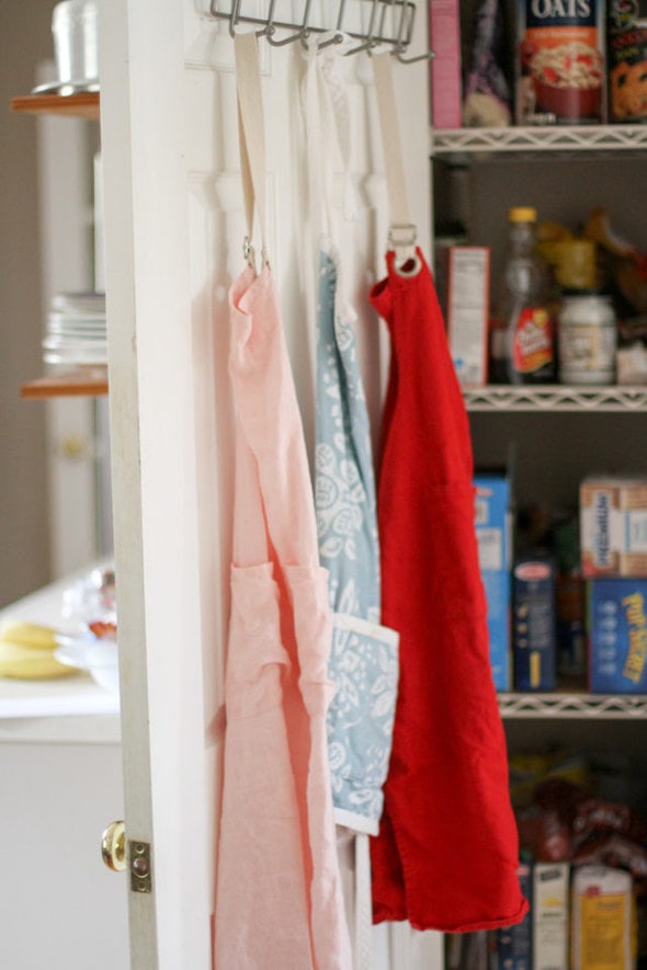 three aprons hanging on hooks.