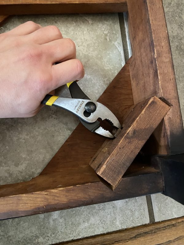 pliers being used to tighten a table leg.