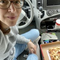 Kristen eating pizza in her van.