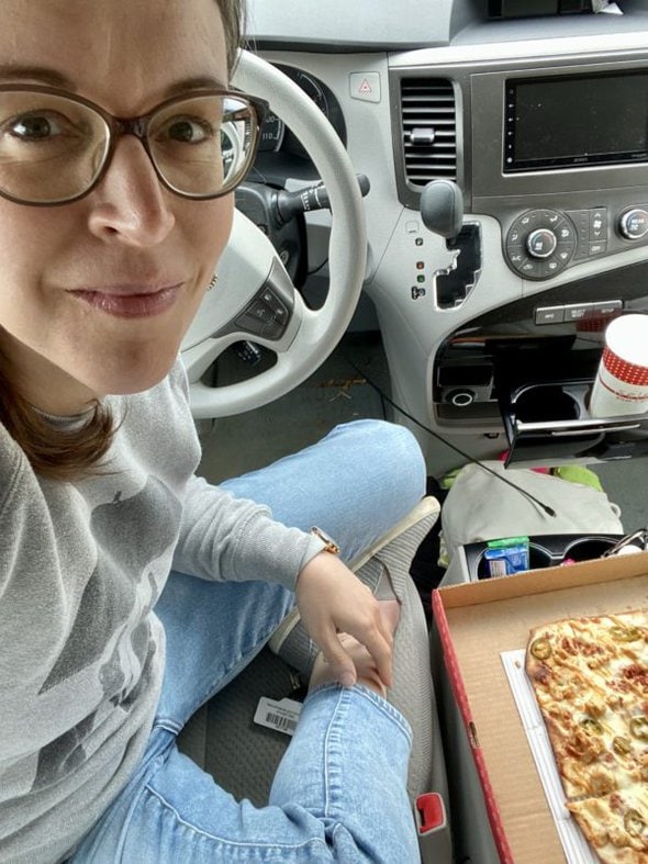 Kristen eating pizza in her van.