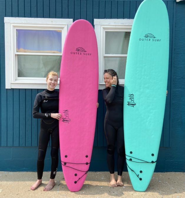 Kristen and Sonia holding surf boards.