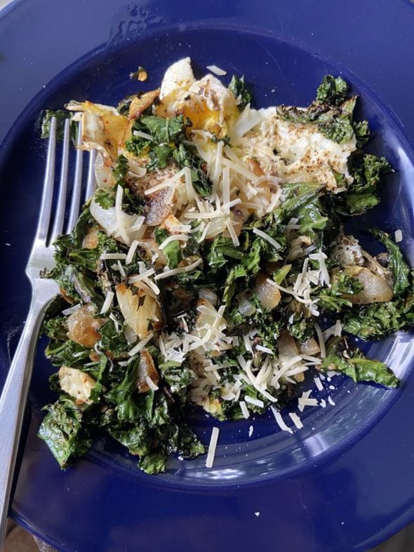 Kale and eggs on a blue plate.