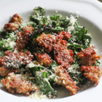 sausage and kale on a white plate.