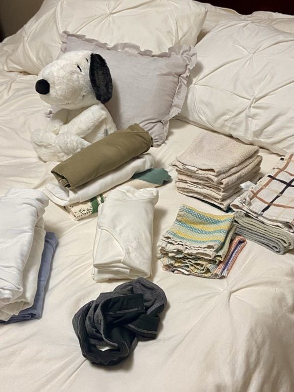 piles of folded laundry on bed.