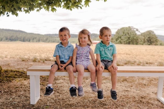 three children sitting on a bench.