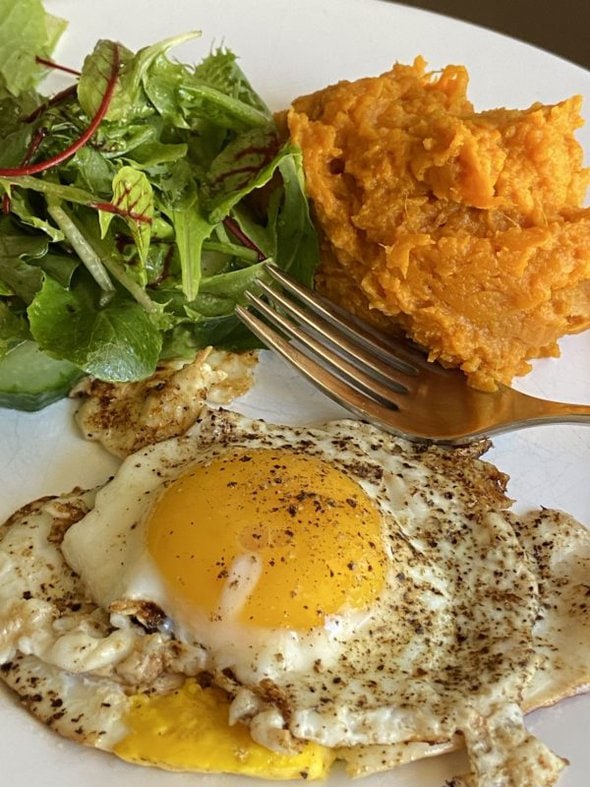 plate of eggs, sweet potatoes, and a salad.