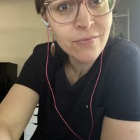 Kristen with earbuds and a scrub top.