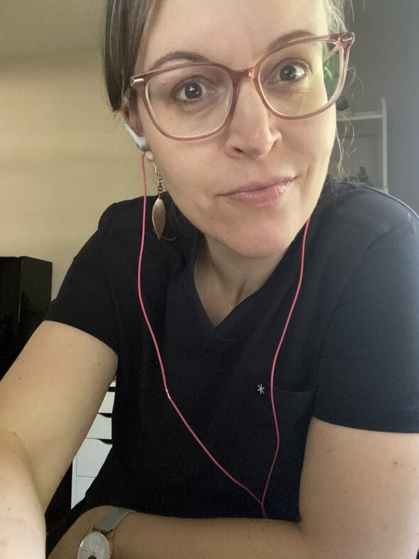 Kristen with earbuds and a scrub top.