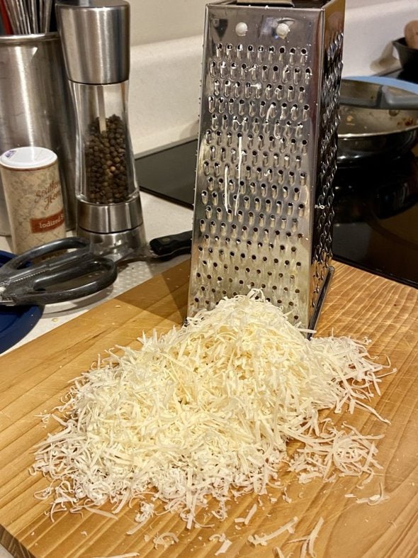shredded Parmesan on a wood cutting board.