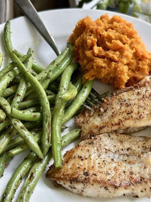 fish, beans, and potatoes on a white plate.